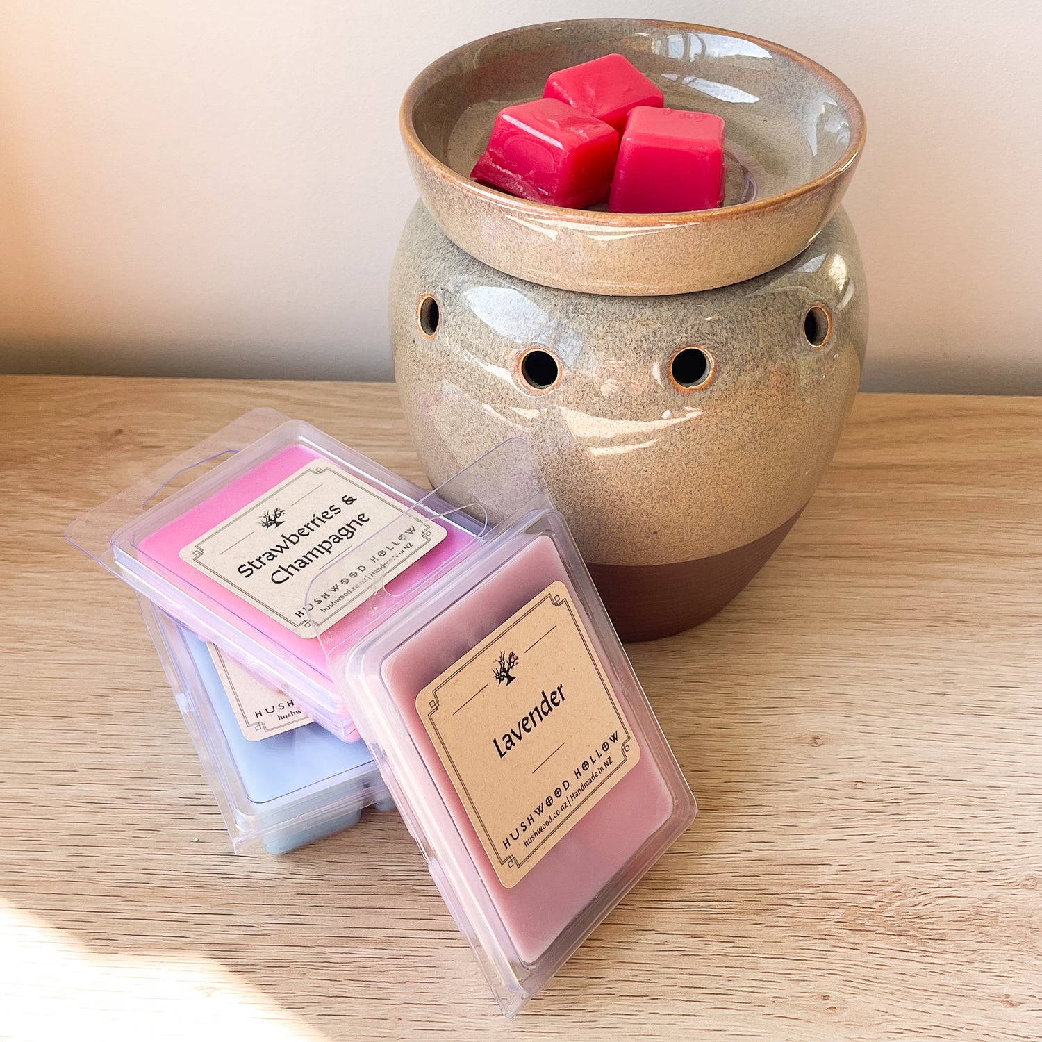 Wax melt warmer with 3 dark pink wax cubes in it and 3 packs of wax melts in blue, light pink and purple